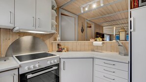 Een kleine keuken met een inbouwfornuis, oven en witte kasten.