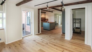 Ein geräumiger Innenraum mit Holzböden, einer Küchenzeile und einer sichtbaren Tür zum Außenbereich.