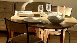Una mesa de comedor con platos, tazones y vasos, con un sofá y sillas al fondo.