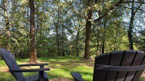 Una terraza con dos sillas Adirondack mirando hacia un área boscosa.