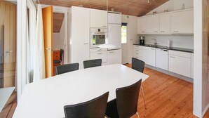 A modern kitchen with white cabinets, a dining table with chairs, and a wooden ceiling. - Nice home in Samsø with kitchen (Samsø)