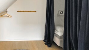 A bedroom with a bed, a wooden hanger, a black curtain, and a white wall. - Stunning home in Sölvesborg with WiFi (Sölvesborg)