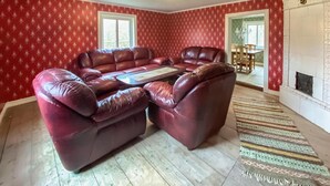 Una sala de estar con papel tapiz rojo estampado, un sofá de cuero, una mesa de centro y una alfombra con diseño.