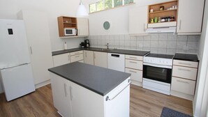 A modern kitchen with white cabinets, a black countertop, a built-in microwave, a coffee maker, and a stove. - Beautiful home in Samsø with WiFi (Samsø)