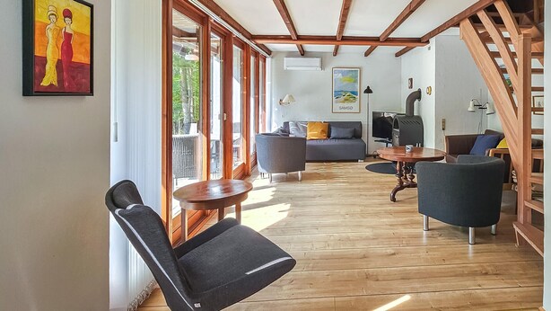A spacious living room with wooden flooring, a sofa, two armchairs, a coffee table, and a fireplace. - Beautiful home in Samsø with WiFi (Samsø)