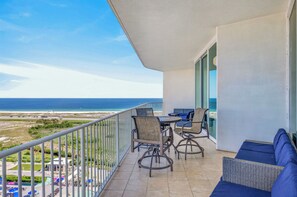 A balcony with a view of the ocean, a table with chairs, and a sofa. - Professionally Decorated Penthouse Unit! ASK ABOUT DISCOUNTS! (Orange Beach)