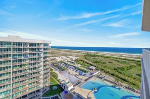 Un hôtel doté de nombreux balcons, d’une piscine et offrant une vue sur la plage et l’océan.