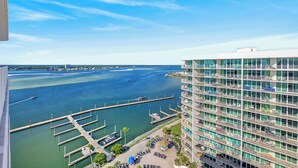 Een hoog hotel met uitzicht op een jachthaven, met balkons, een zwembad en een steiger.