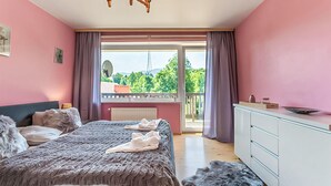 Un dormitorio con cama, cómoda y balcón con vistas a la vegetación.
