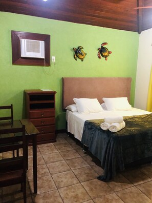 A bedroom with a bed, a wooden dresser, a chair, and a wall-mounted air conditioner.