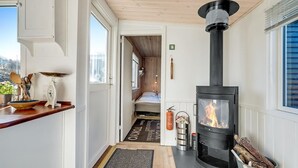 Tunnelmallinen sisustus, jossa on puukamiina, sänky ja näkymä ulos.