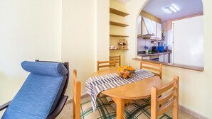 A compact living space with a dining table, chairs, a sofa, and a kitchen area with shelves and appliances. - 2 bedroom awesome apartment in Oropesa del Mar (Oropesa del Mar)