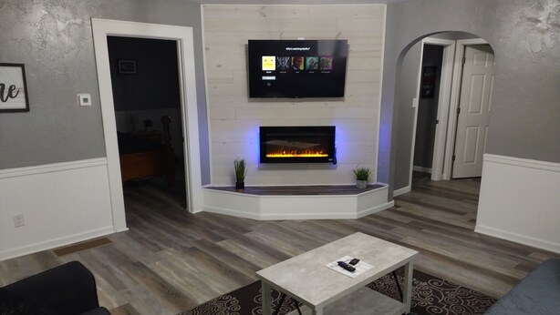 Een moderne woonkamer met een open haard, een flatscreen televisie erboven en een salontafel in het midden.