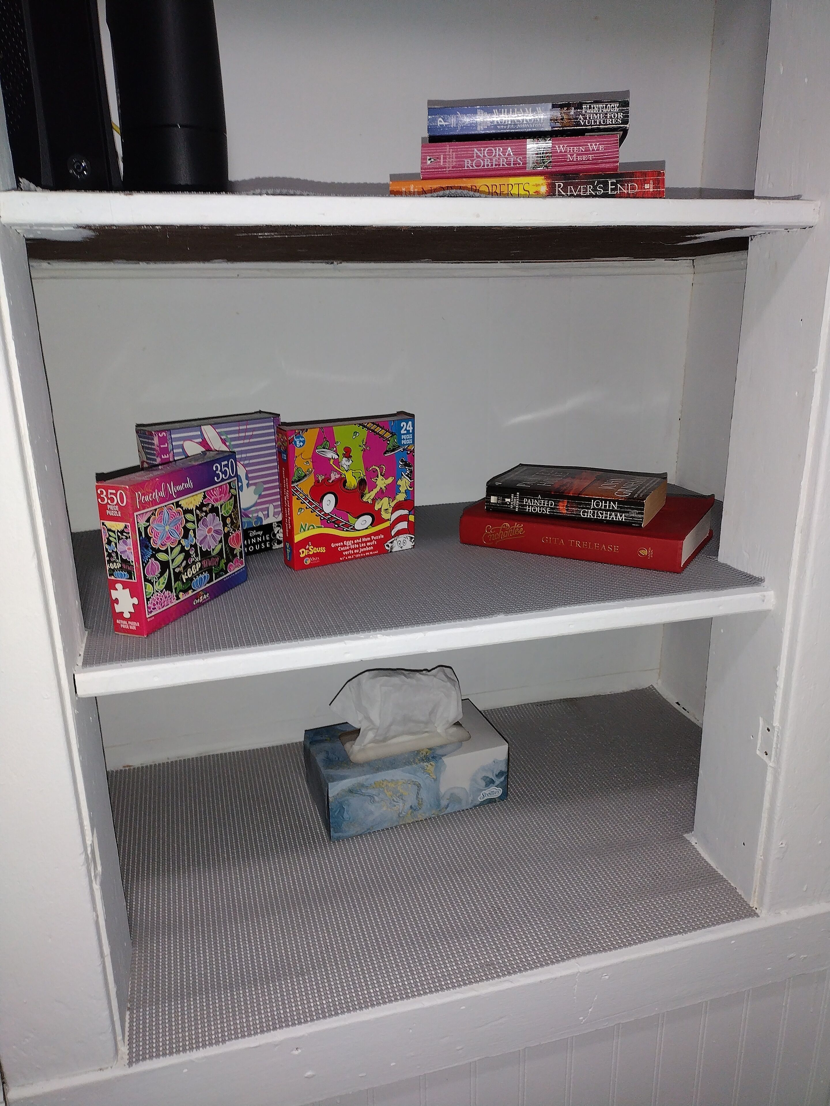 Una estantería con varios libros y una caja de rompecabezas.