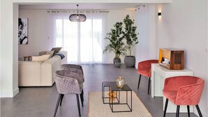 A modern living room with a sofa, two armchairs, a coffee table, and a TV on a stand. There are potted plants and a large window with curtains. - Amazing home in La Chapelle-Vendômoise (La Chapelle-Vendômoise)