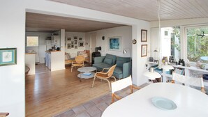 Ein geräumiger Wohnbereich mit Sofa, Sesseln, einem Esstisch und einer Küche im Hintergrund.