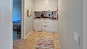 A narrow kitchen with white cabinets, a small refrigerator, and a wooden floor. - 1 bedroom stunning home in Auktsjaur (Auktsjaur)