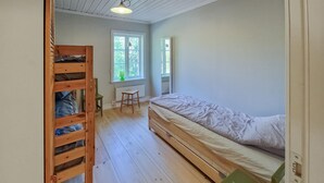 A bedroom with a bunk bed, a single bed, a window with a view of trees, and a radiator. - 1 bedroom stunning home in Auktsjaur (Auktsjaur)