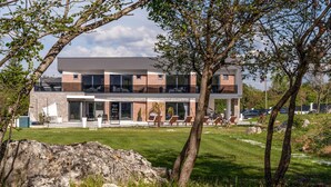 A modern two-story house with a large glass balcony, a well-maintained lawn, and a rock garden. - Pet friendly home in Radosic (Radosic)