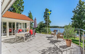 Eine Terrasse mit Sitzgelegenheiten im Freien, eine schwedische Flagge und ein Blick auf einen See.
