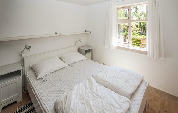 A bedroom with a bed, bedside tables, a lamp, and a window with a view of greenery. - Awesome home in Samsø with WiFi (Samsø)