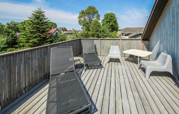 A wooden deck with a table and two chairs, surrounded by a wooden fence. - Awesome home in Samsø with WiFi (Samsø)