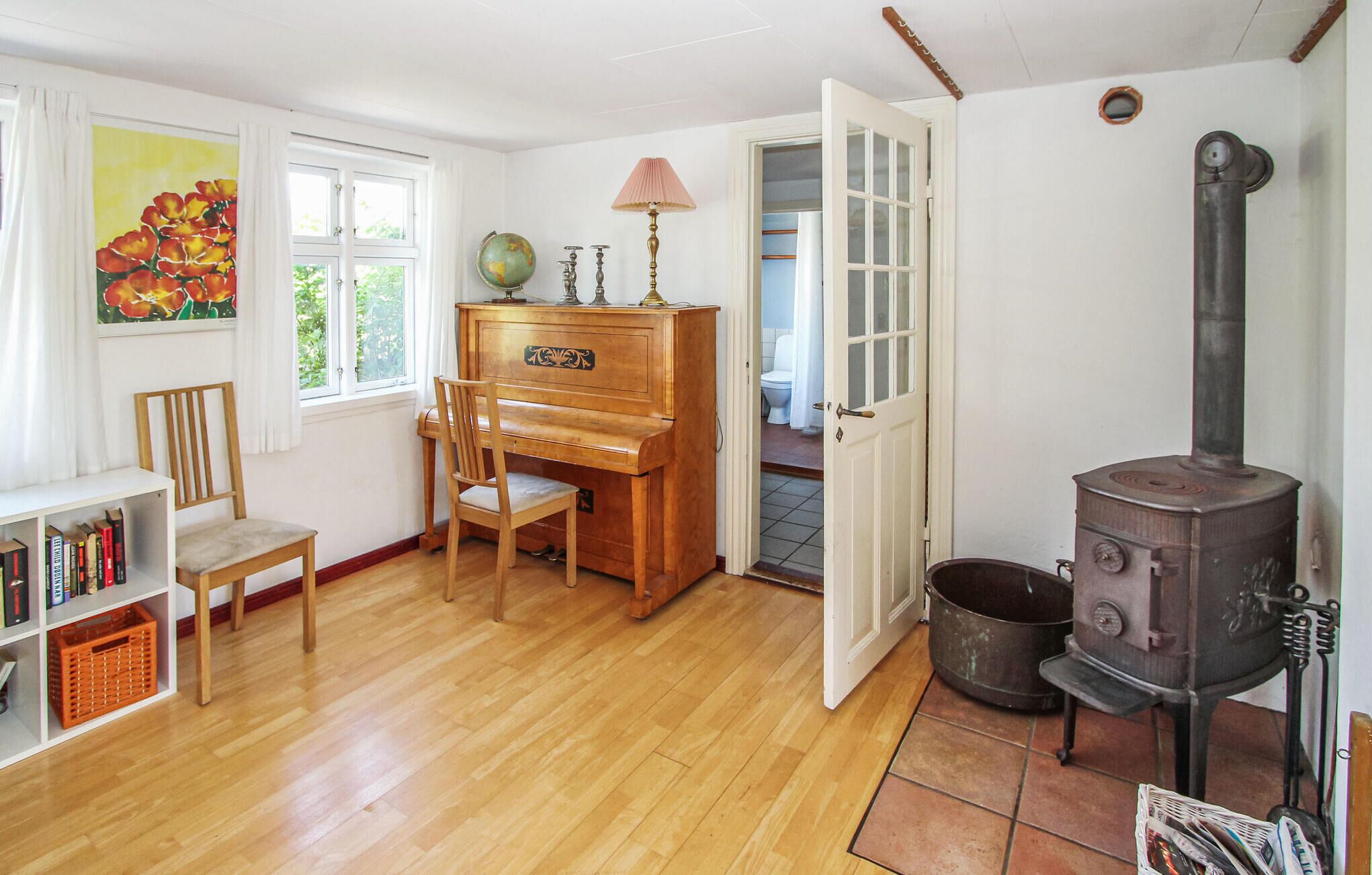 Quarto acolhedor com um piano de madeira, uma estante de livros, um globo terrestre e uma lareira a lenha.