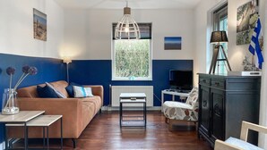 Een moderne woonkamer met een bruine bank, een klein tafeltje, een televisie en een open haard.