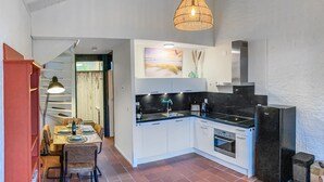 Una cucina moderna con mobili bianchi, un piano di lavoro nero e un forno integrato. C'è un'area pranzo con tavolo e sedie, e un lampadario sopra la cucina.