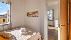 A bedroom with a bed, a window, a radiator, a painting, and a view of the outside. - 1 bedroom stunning apartment in Varazze (Varazze)