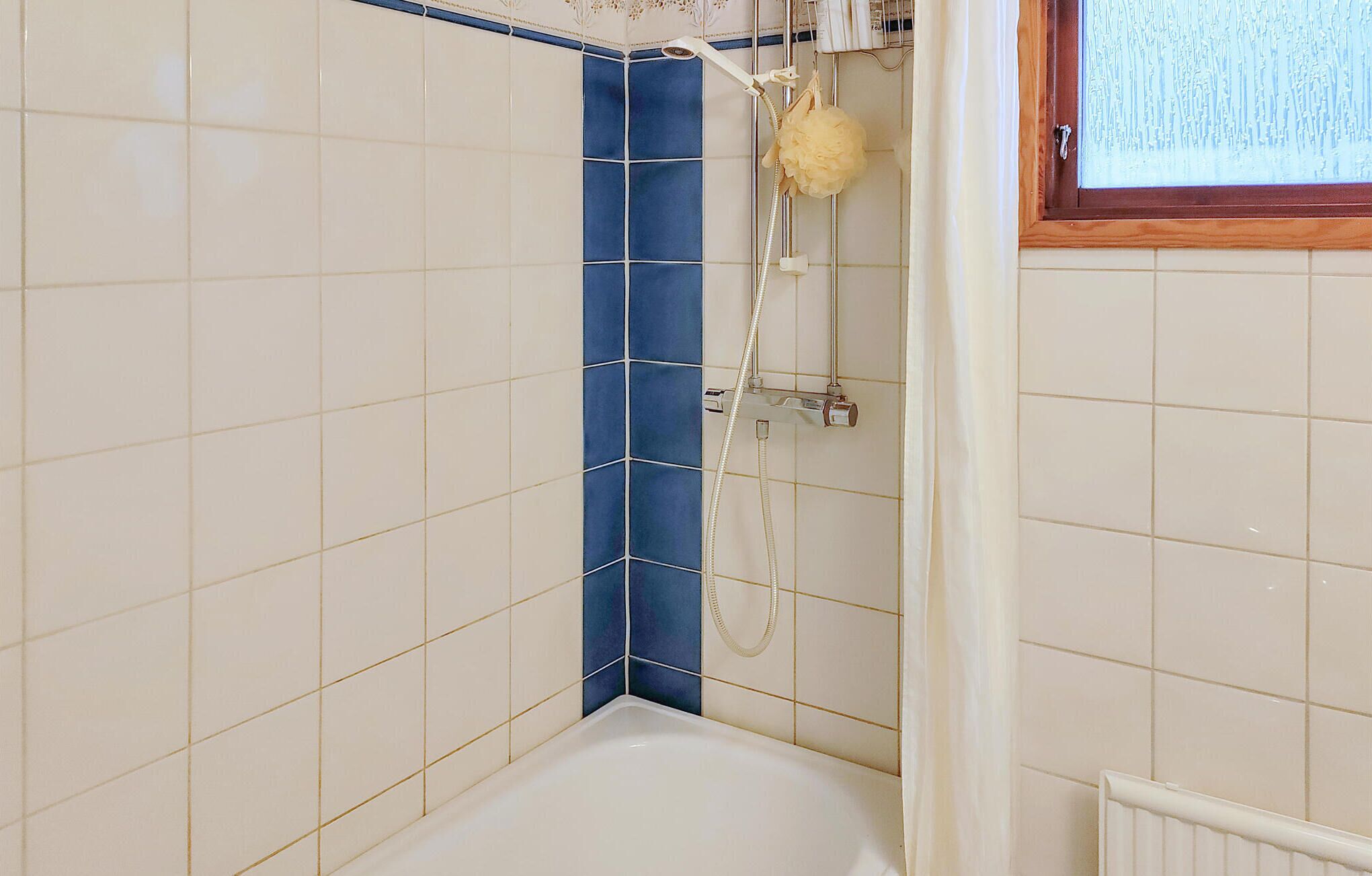 Ein Badezimmer mit Badewanne, Dusche und Fenster.