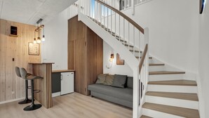 Um interior moderno com escadas, um sofá, área de refeições e cozinha.