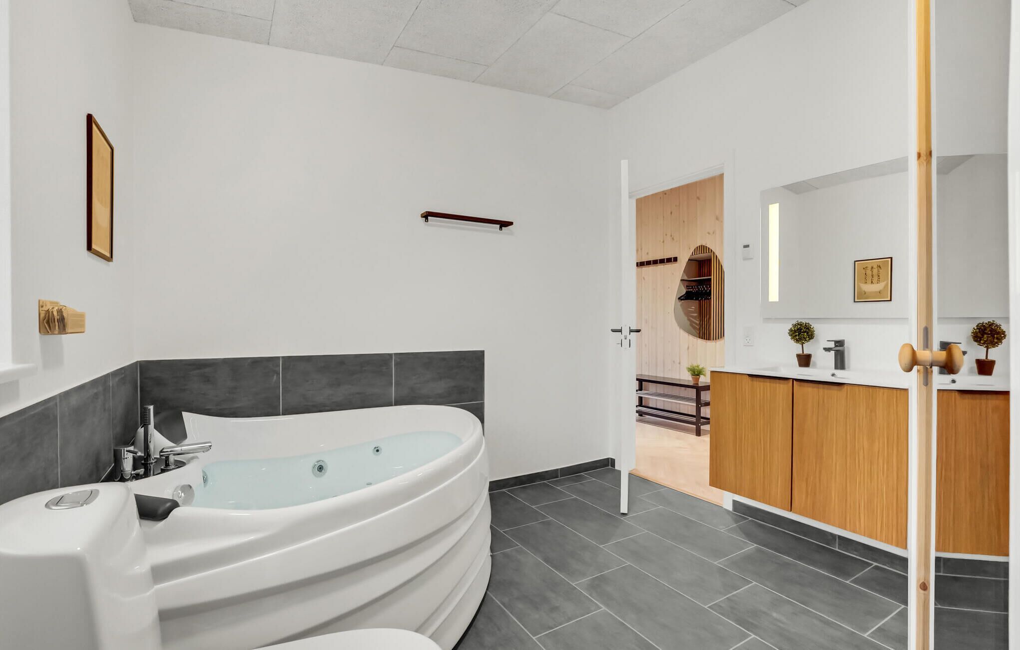 Un bagno moderno con una vasca freestanding, un mobile bagno in legno e uno specchio grande.