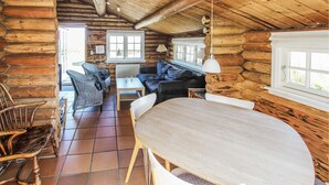 Et interiør af en træhytte med spiseområde, sofa og stole.