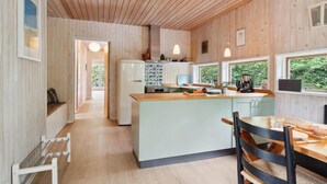 Cocina moderna con paneles de madera, una isla central, iluminación colgante y vistas al exterior.