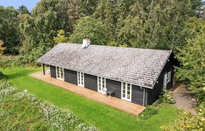 Ein zweigeschossiges Haus mit geneigtem Dach, einer Veranda und einem kleinen Garten.