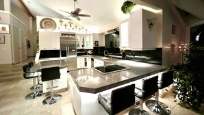 Una cocina moderna con una isla central, taburetes de bar y un ventilador de techo.