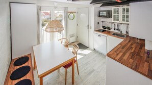 A compact kitchen with a dining area, wooden flooring, and a view through the door. - Lovely apartment in Samsø (Samsø)