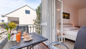 Varanda com mesa posta para o café da manhã, cama com vista e uma pequena janela.