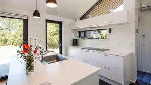 A modern kitchen with white cabinetry, a built-in oven, and a window overlooking greenery. - Awesome home in Samsø with WiFi (Samsø)