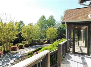 Stroll along the garden pathway to a serene outdoor space with a wooden deck overlooking a lush area.