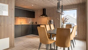 Una cucina moderna con pareti in legno e un'area pranzo con tavolo e sedie.