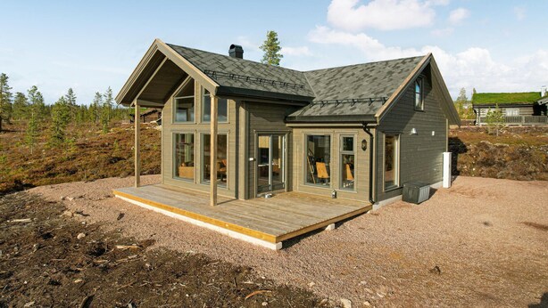 Una casa moderna con ampie finestre, un pontile in legno e un tetto spiovente.