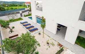 A modern outdoor pool area with sun loungers and a small table, surrounded by potted plants and a view of the countryside. - Pet friendly home in Skrip (Skrip)