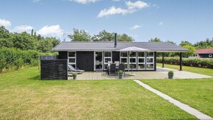 Ein modernes Haus mit Terrasse, überdachtem Patio und Garten.
