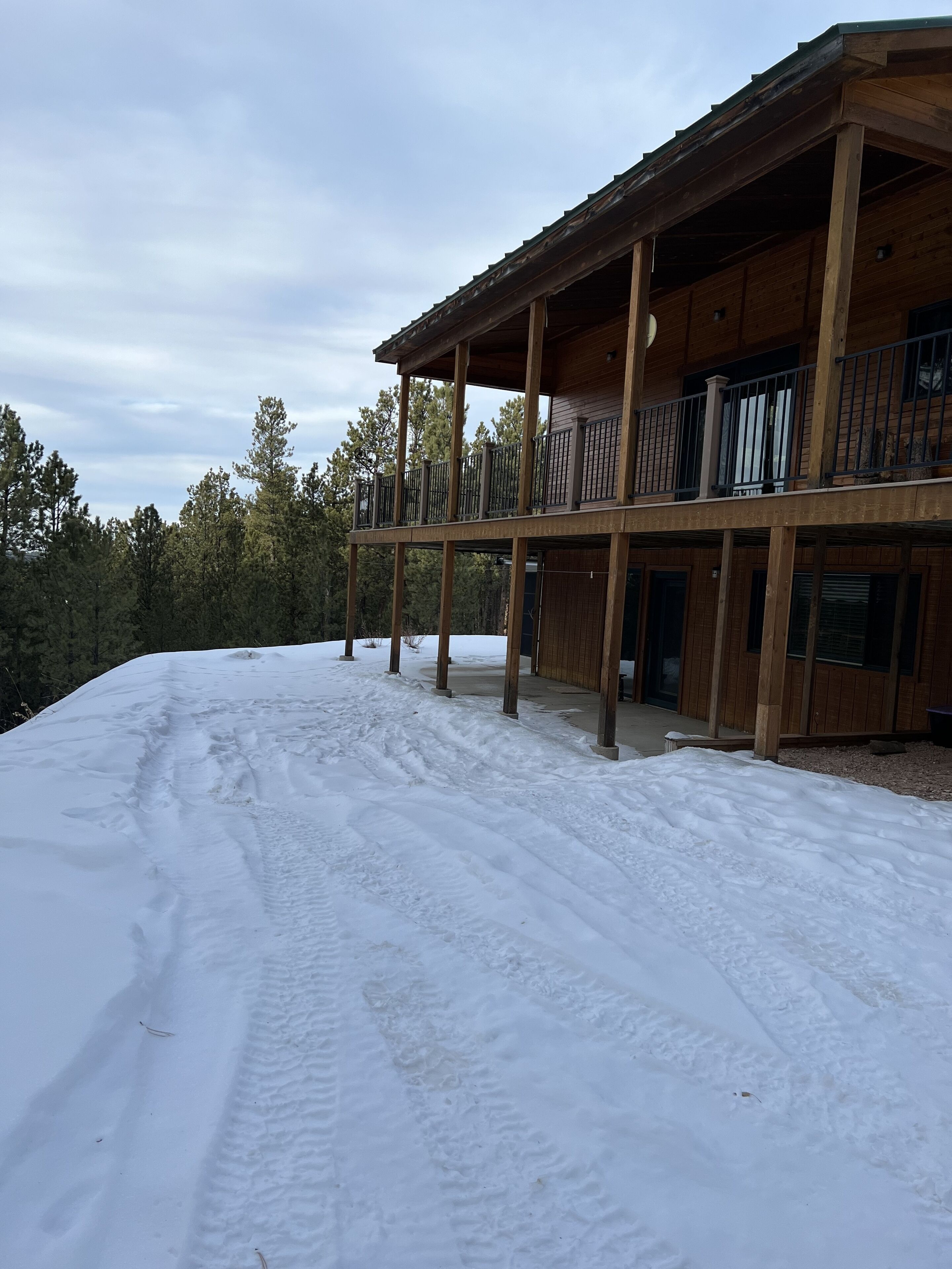 Une cabane en bois dotée d’un porche abrité et dont le sol est recouvert de neige.