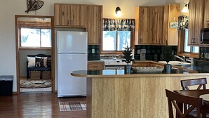 A spacious kitchen with wooden cabinets, a central island, and a dining area with a table and chairs. - Cozy cabin in the beautiful Black Hills (Newcastle)