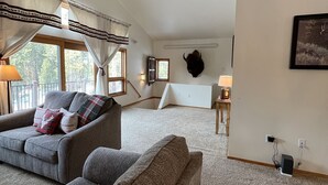 A spacious living room with a ceiling fan, a fireplace, and a large window. - Cozy cabin in the beautiful Black Hills (Newcastle)
