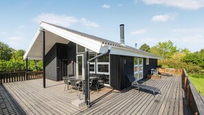 A wooden deck with a covered outdoor seating area, a chimney, and a number '2' on the building. - 2 bedroom nice home in Samsø (Samsø)