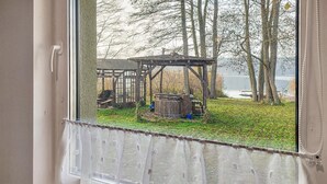 Een raam met uitzicht op een houten constructie en een waterpartij.